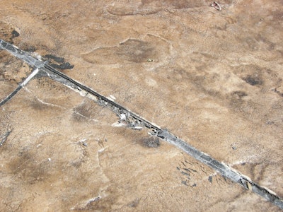 This photograph shows a decorative concrete overlay where the original control joint was not honored. The concrete underneath the overlay continued to move at the original joint causing cracking and damage in the overlay.