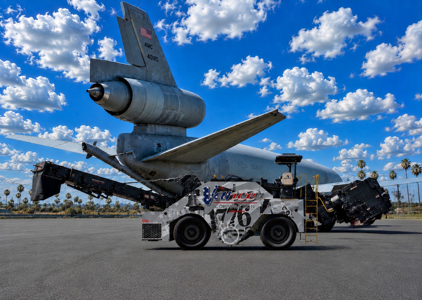 Decommissioned aircraft tail suspended above white ground support tug vehicle in desert aviation facility