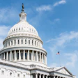 U.S. Capitol Building dome with neoclassical architecture and American flag against blue sky