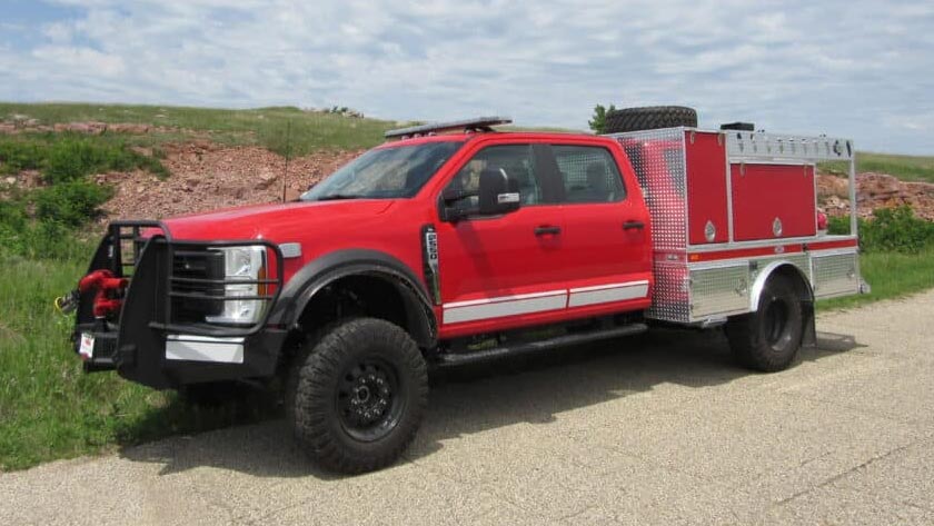 Red and silver fire truck with emergency equipment parked on rural road