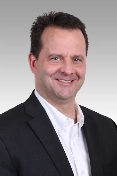 Professional headshot of a man in business attire smiling at the camera