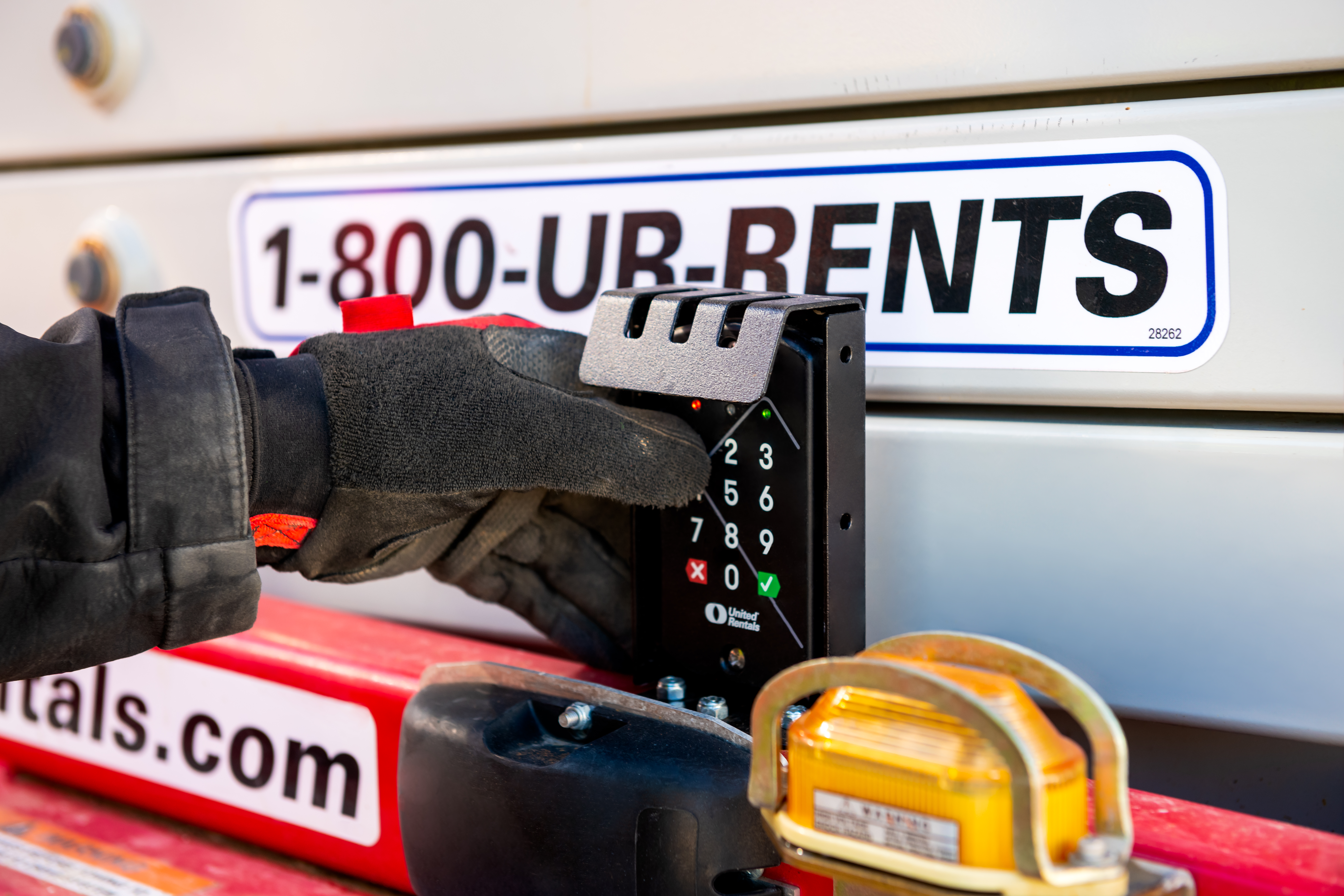 Worker using payment terminal on rental equipment truck with 1-800-UR-RENTS phone number and tools visible