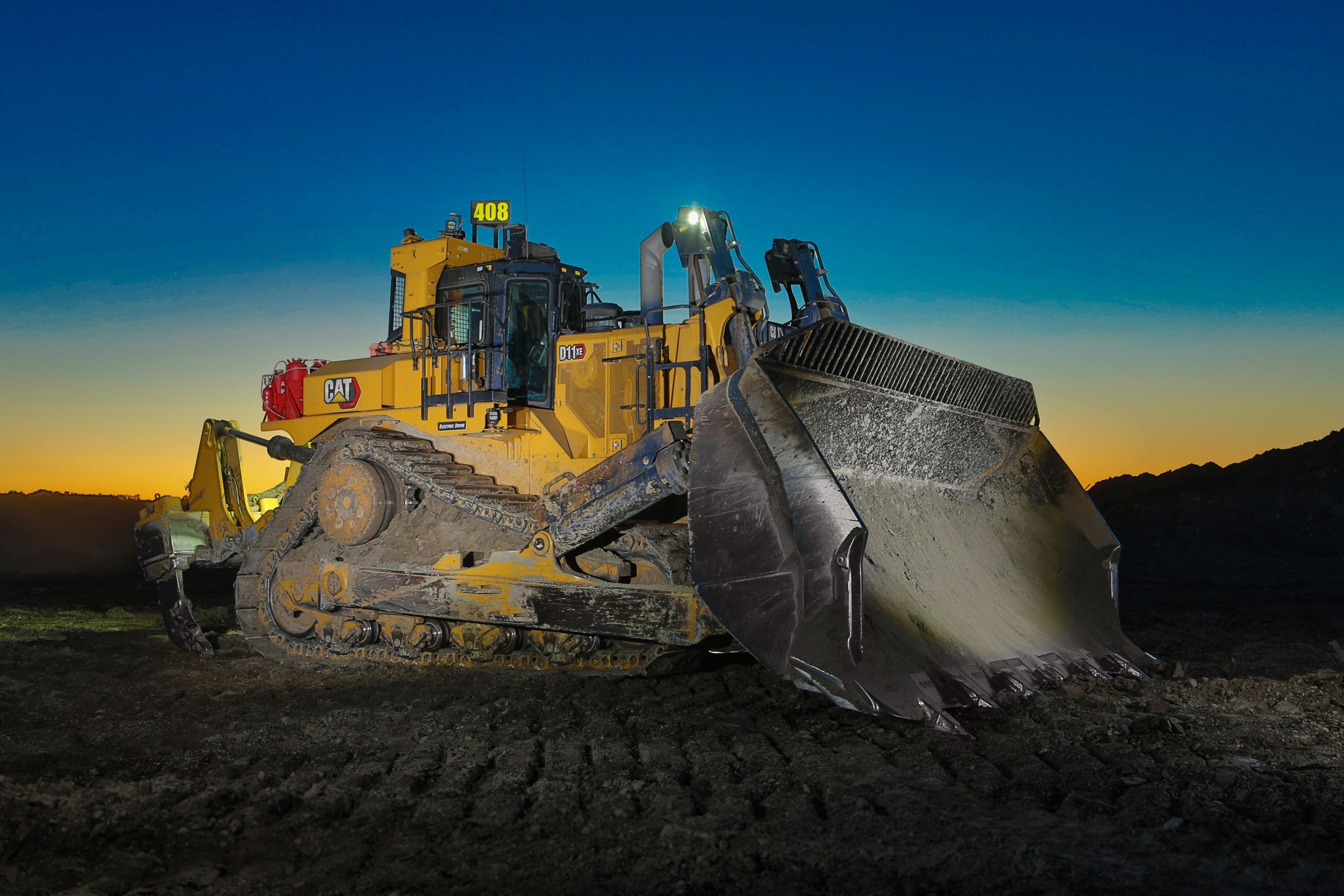 Caterpillar bulldozer with raised blade at sunset on construction site