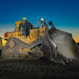 Caterpillar bulldozer with raised blade at sunset on construction site