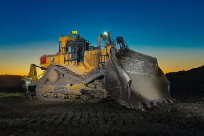 Caterpillar bulldozer with raised blade at sunset on construction site
