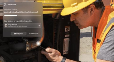 Construction worker in hard hat and safety vest inspecting hydraulic equipment during site inspection