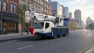 White and blue Tadano mobile crane truck parked on urban street with city buildings in background